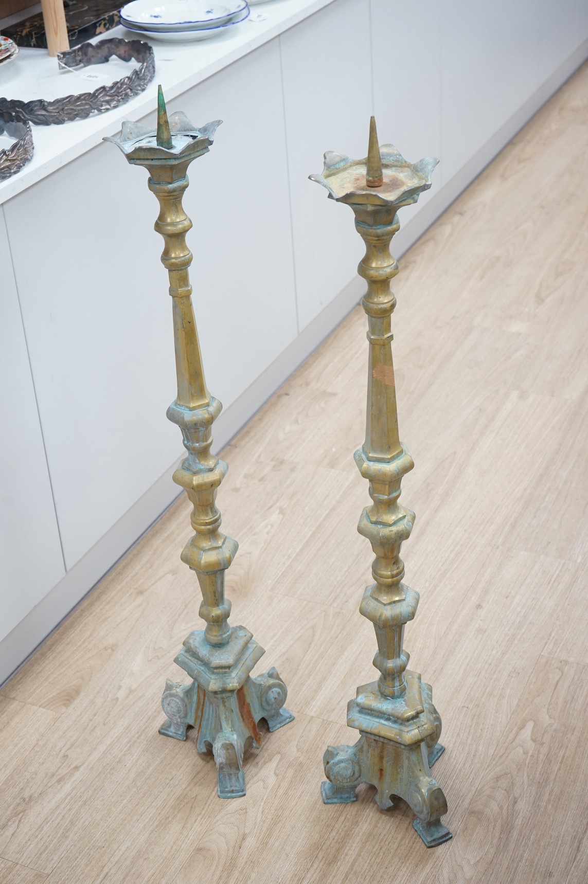 A pair of brass floor standing pricket candlesticks, 110cm high. Condition - both have verdigris and one top plate is cracked.